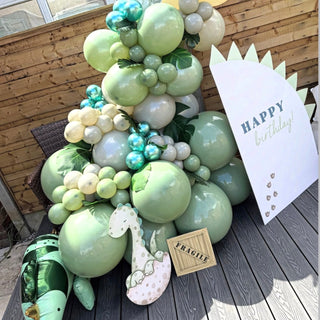 Dinosaur Birthday Backdrop | Sage green balloon display with personalized backdrop, dinosaur cut-out and themed props