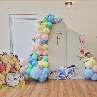 Winnie the Pooh Christening Backdrop | Pastel balloon display with Pooh, Eeyore, honey pots and religious cross
